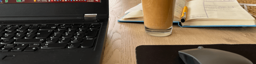 Officebild mit Laptop, Kaffee und Notizbuch