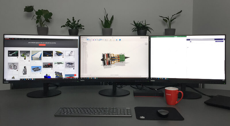 drei Monitore in einem Büro zeigen 3D Konstruktionen und Office-Anwednugen
